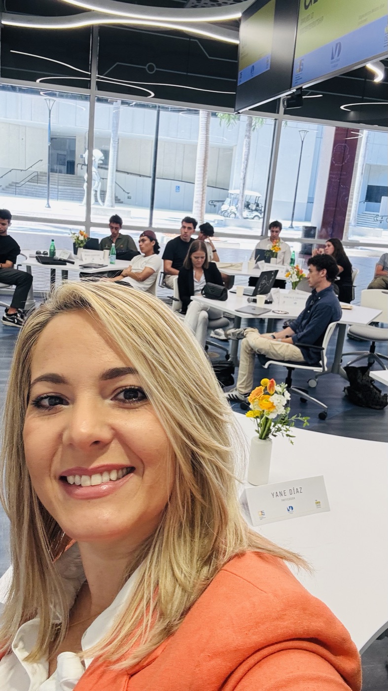 Yane en su mesa de profesora en Miami Dade College, con estudiantes de universidades de España detrás
